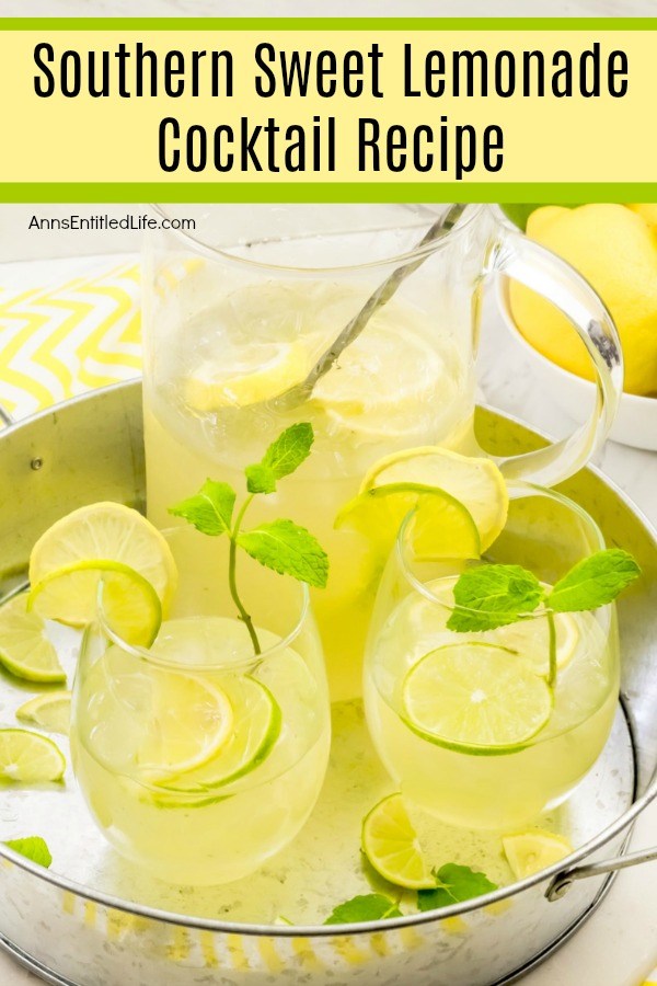 An front view of a pitcher of southern lemonade and two filled glasses on a galvanized tray. There is a bowl of lemons in the upper left, a small bowl of cut limes below that.