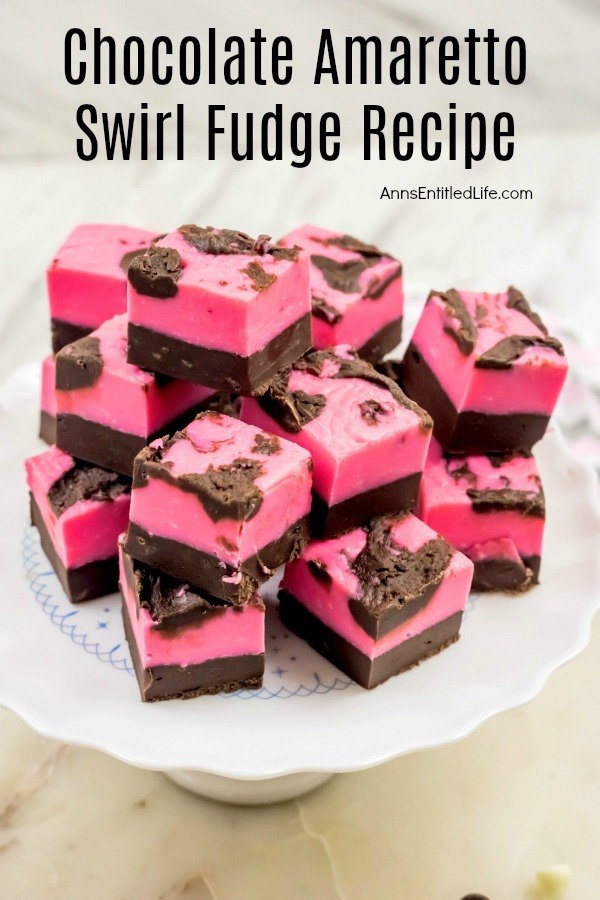 A white cake stand with a blue inlay patter that is filled with chocolate amaretto swirl fudge stacked three-high