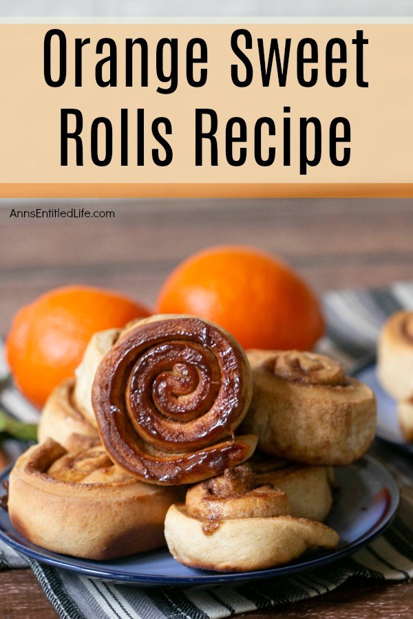 six orange sweet rolls on a blue plate, two fresh oranges in the background