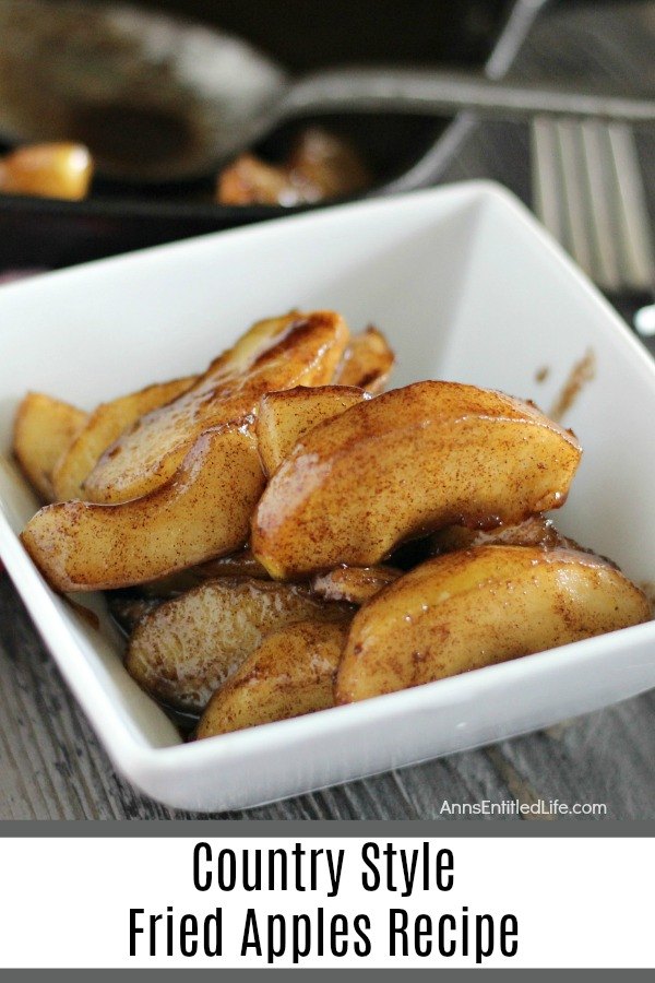 country-style fried apples in a white bowl on a grey board, spoon in a skillet in the background