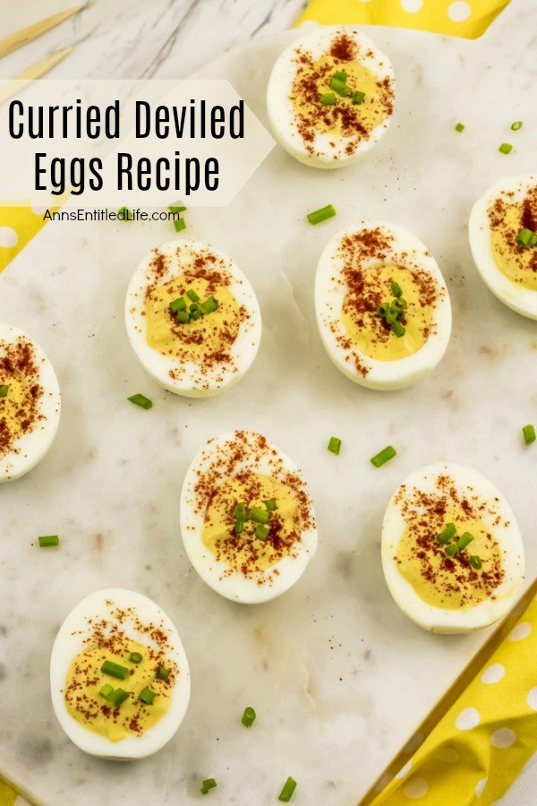 6 half hard boiled eggs with curry filling, paprika and chives garnish on a white background