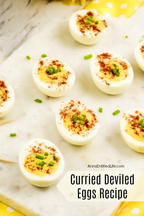 7 half hard boiled eggs with curry filling, paprika and chives garnish on a white background