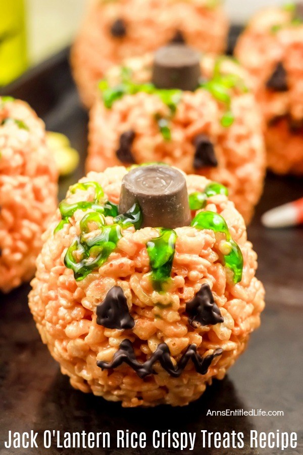 5 jack o'lantern halloween treats made with crispy rice cereal on a dark tray