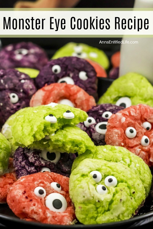 multicolored crinkle cookies with candy eyeballs in them on a dark tray