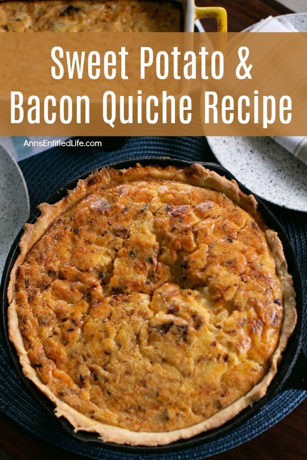 whole sweet potato and bacon quiche, in a black pan, on a blue placemat. A napkin and silverware rests to the upper right, a pan of potaties is in the upper left