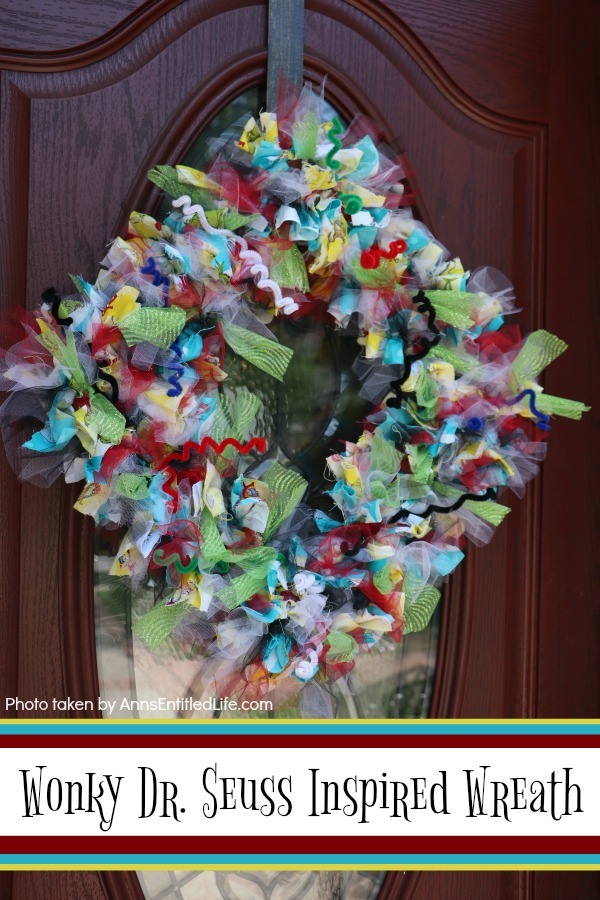 multicolored wreath with a Dr. Seuss theme hung diagonally on a brown front door with a window