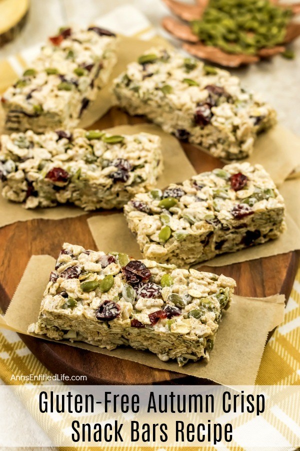 5 Gluten-Free Autumn Crisp Snack Bars served on small pieces of butcher paper, on top of a brown cutting board. a dish of pepitas is in the upper right.