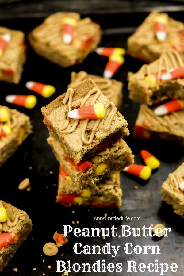 stack of peanut butter candy corn blondies on top of a black counter, dropped candy corn for garnish, and more of the blondies surrounding the stack