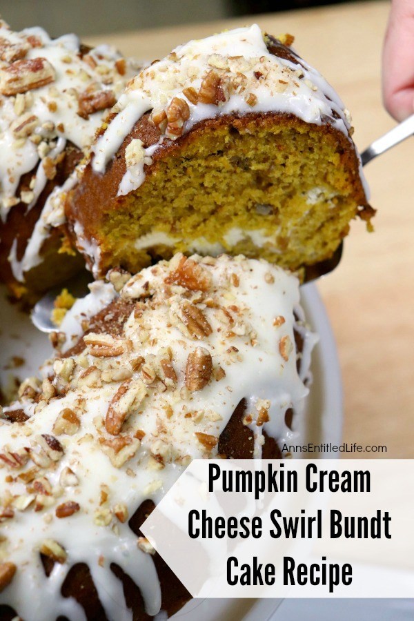 a slice of Pumpkin Cream Cheese Swirl Bundt Cake being lifted from the main cake on a silver serving utensil