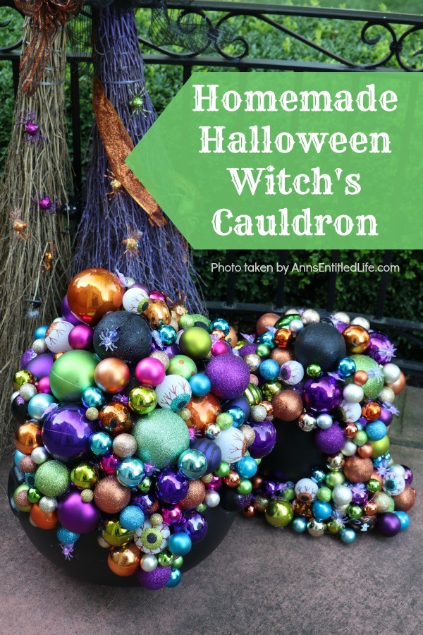 multicolored bulbs formed to imitate bubbles flowing from the cauldron base. There are two cauldrons, one large, one small. Two decorated brooms are in the background, outside on a porch