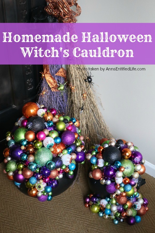 multicolored bulbs formed to imitate bubbles flowing from the cauldron base. There are two cauldrons, one large, one small. Two decorated brooms are in the background, outside on a porch