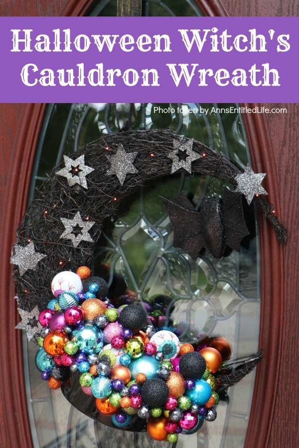 multicolored bulbs formed to imitate bubbles flowing from the cauldron attached to a half-moon black prelit wreath, hanging on a brown door with a glass insert