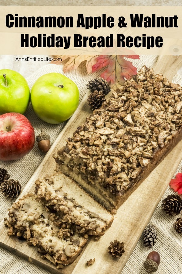 An overhead view of a  loaf of cinnamon apple and walnut bread on a wood cutting board, two slices are cut at the front. Several apples are to the left of the cutting board, as well as several acorns on the right and left.