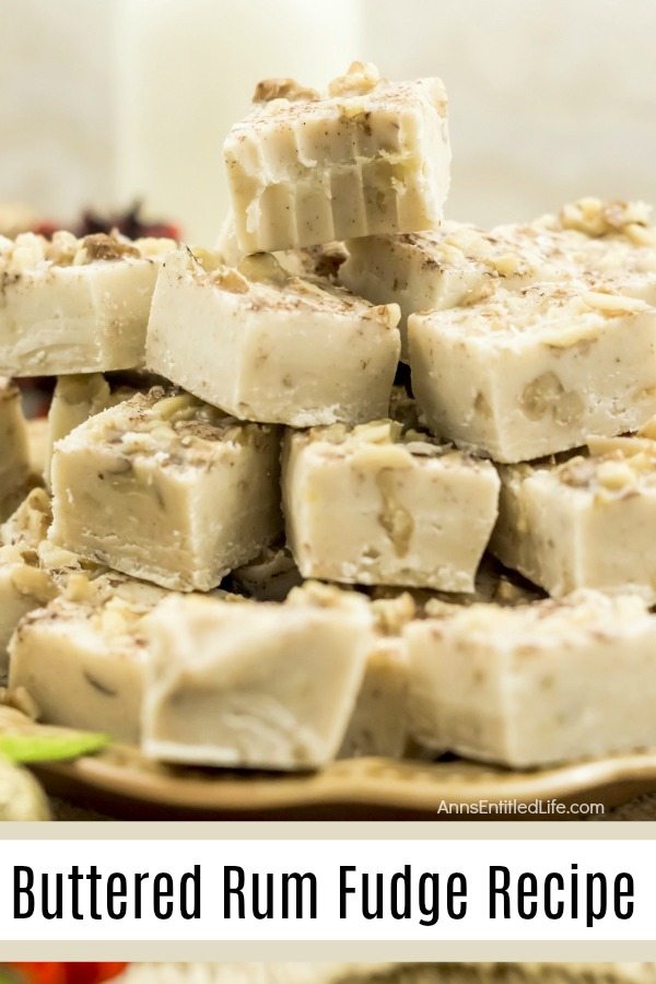 A straight-on view of square-cut pieces of butter rum fudge on a gold plate. The top piece has a bite missing to see the inside. The plate is set upon burlap.