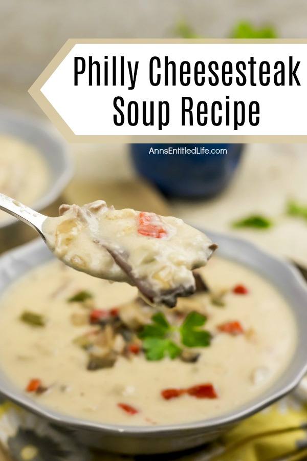 A spoonful of Philly chesesteak soup being lifted from a blue bowl filled with Philly cheesesteak soup garnished with mushrooms and peppers