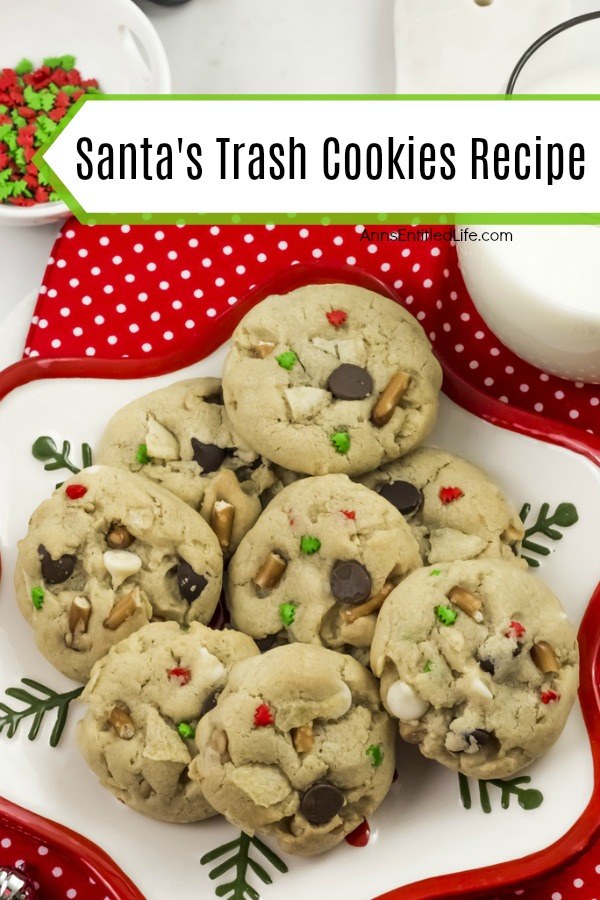 An overhead view of a plate of a Christmas themed plate filled with 8 Santa trash cookies. There is a glass of milk in the upper right, and a bowl of Christmas sprinkles in the upper left.