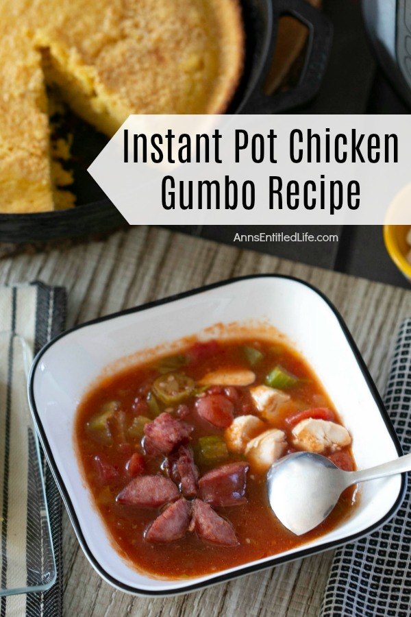 white bowl with blue rim filled with chicken gumbo with a spoon laying inside the bowl, cornbread in a pan with one piece removed, atop of weathered tabletop