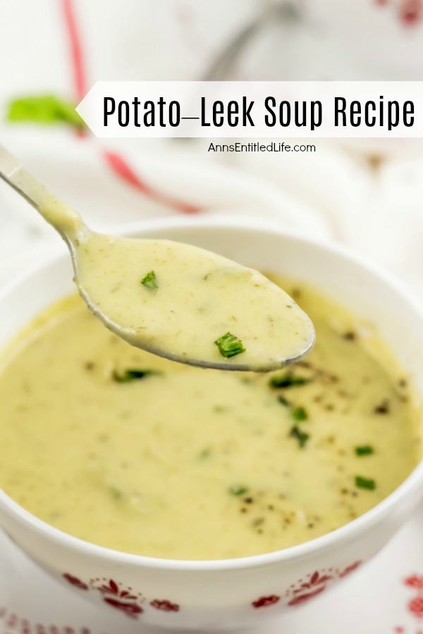 A spoonful of potato-leek soup is lifted from the red patterned white bowl that is full of the soup