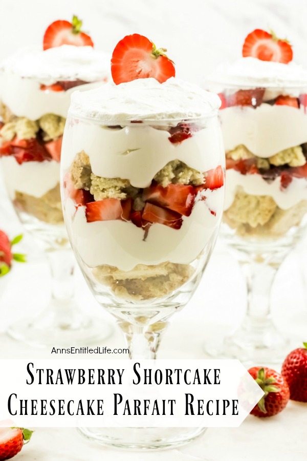 close-up of three strawberry cheesecake partfait desserts on a white background surrounded by fresh strawberries