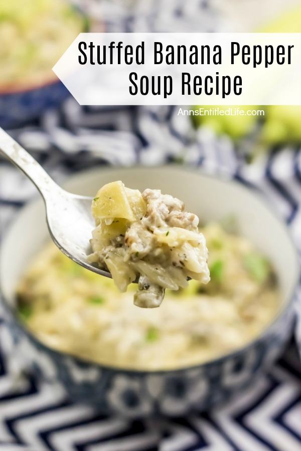 A spoon full of stuffed banana soup is at the forefront of this image. A black bowl with a white interior is filled with banana pepper soup, decorated with sliced banana peppers is in the background. This is set upon a black and white chevron napkin.