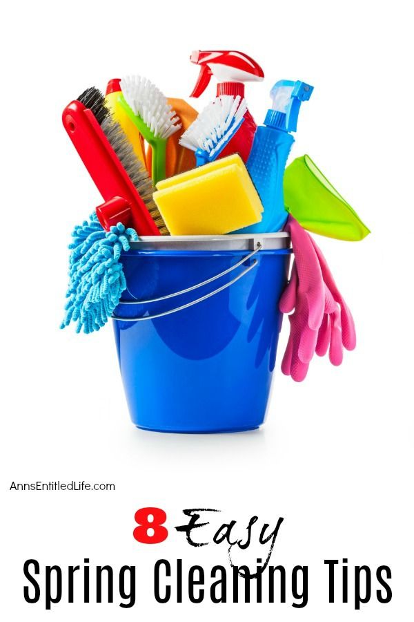 Blue bucket filled with household cleaning supplies including brushes, sponges, rags, and gloves.