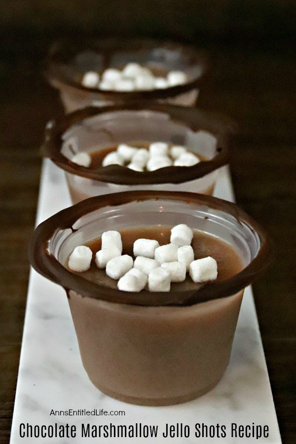 Two chocolate marshmallow jello shots on top of a red and white napkin, a spoon on the left.