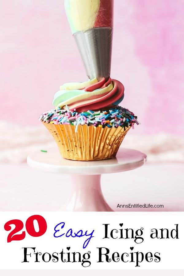 A chocolate cupcake with sprinkles on a white cake plate, a tube of rainbow frosting is squirting in a swirl down onto the middle of the cupcake