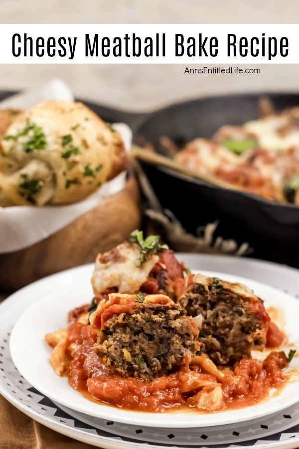 A serving of cheesy meatballs on a white dish is front and center. A basket of knot rolls are seen in the back left, the skillet pan of the remaining cheesy meatball bake is in the back right.