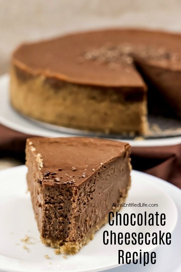 And piece of chocolate cheesecake with a bite removed on a white serving plate, the remainder of the chocolate cheesecake on a white serving plate in the background, all on top of a brown fabric.