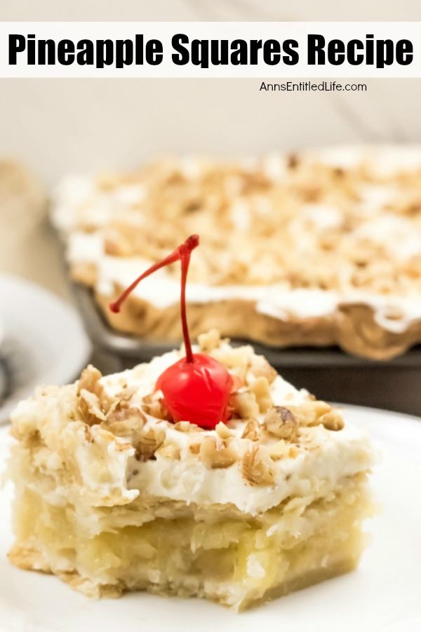 A piece of pineapple square on a white plate, a small portion removed, a pan of frosted pineapple squares topped with crushed walnuts in the background
