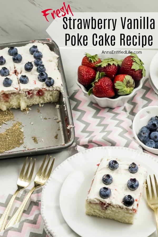 A piece of strawberry vanilla poke cake on a white plate is in the lower right of the image, gold silverware is on the table to the left and right. The remaining cake in the pan is to the upper left, a bowl of strawberries and a bowl of fresh blueberries are in the upper right.