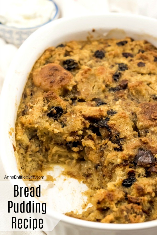 A close-up of white casserole bowl filled with baked bread pudding, one serving removed.