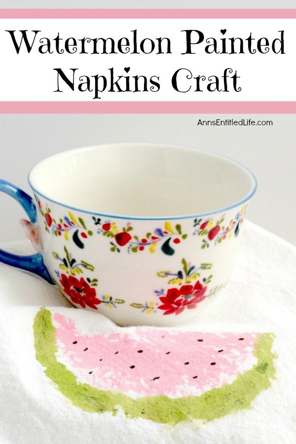 A white napkin with a hand painted watermelon slice on it, with a pretty flower teacup behind it