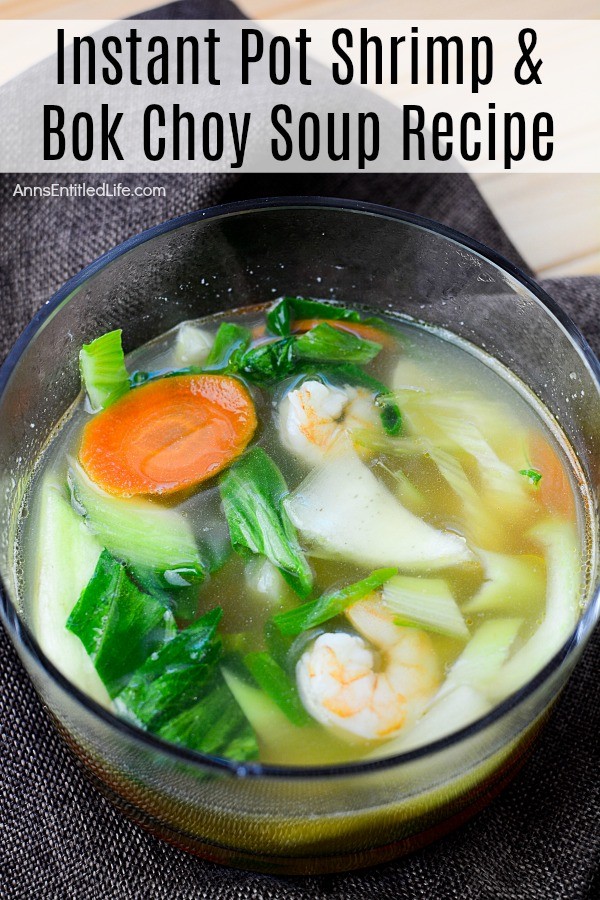 Overhead shot of shrimp and boy choy soup in a clear bowl on a navy blue napkin