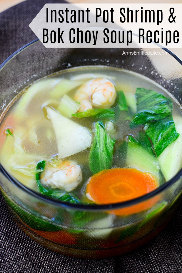 Close-up, overhead view of shrimp and boy choy soup in a clear bowl on a navy blue napkin