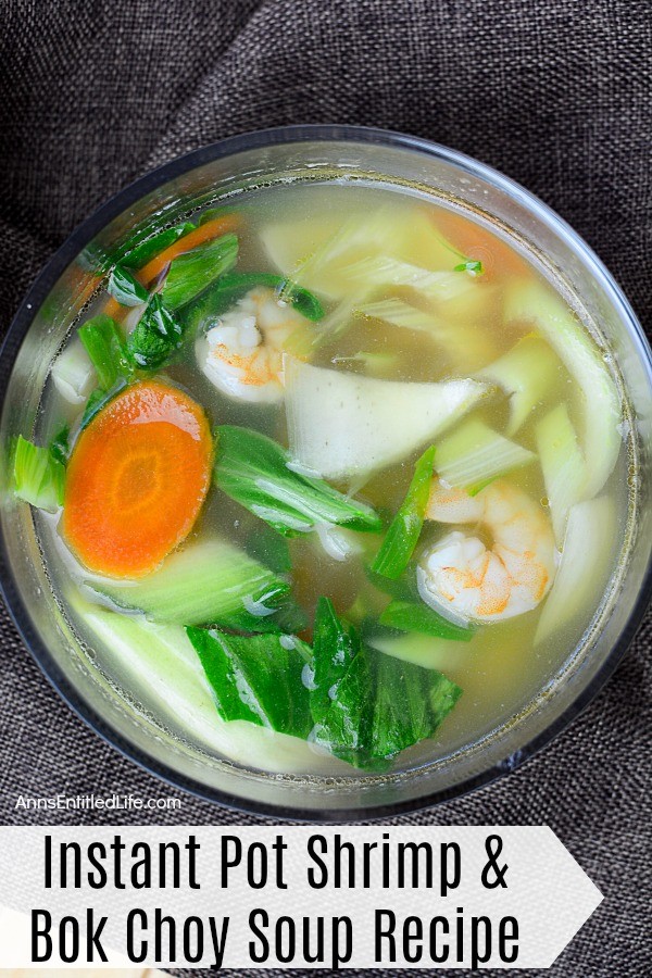 Overhead shot of shrimp and boy choy soup in a clear bowl on a navy blue napkin