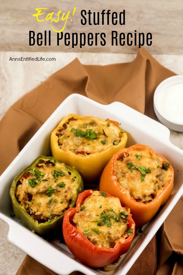 4 baked bell peppers (1 red, 1 green, 1 orange, 1 yellow) filled with rice and beef mixture, in a white baking dish set atop a brown napkin