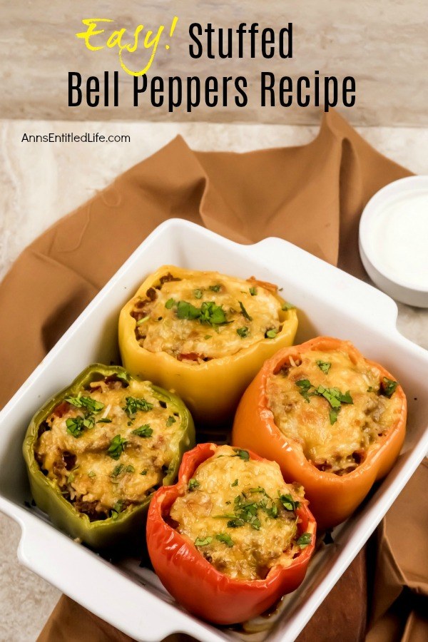 4 baked bell peppers (1 red, 1 green, 1 orange, 1 yellow) filled with rice and beef mixture, in a white baking dish set atop a brown napkin