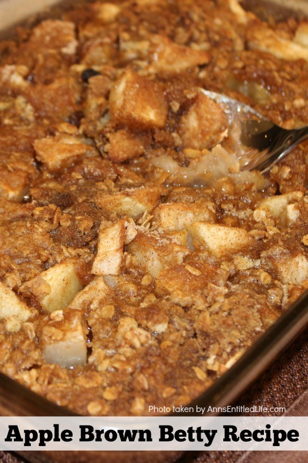 Close-up photo of a 13x9 pan filled with an apple brown betty dessert, a spoon in the center of the pan starting to lift a taste of the dessert