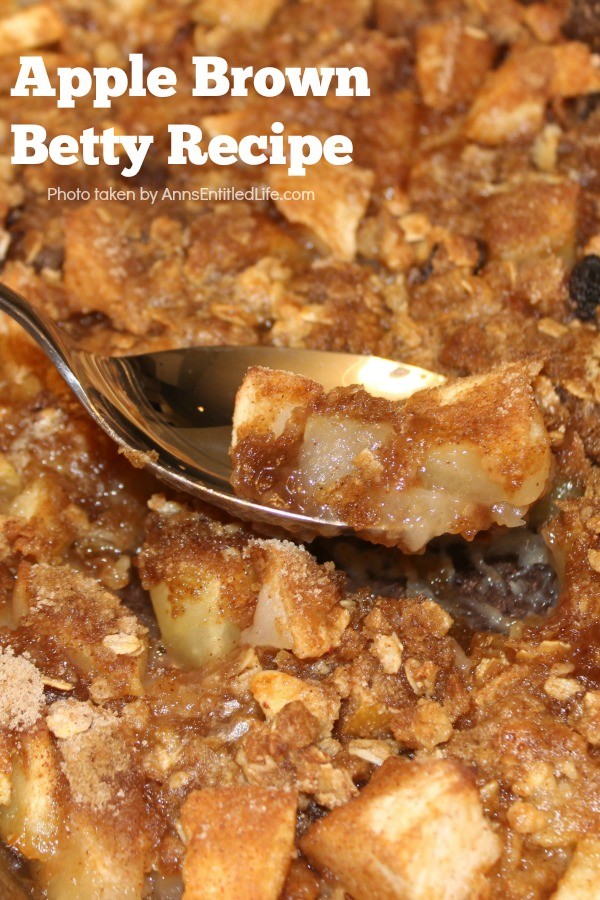 Close-up photo of a 13x9 pan filled with an apple brown betty dessert, a spoon in the center of the pan starting to lift a taste of the dessert
