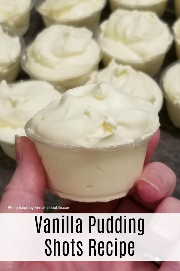 a vanilla pudding shot in a plastic soufflé cup at the forefront being held in a woman's hand, 10 more pudding shots in the background, all on a slate kitchen island countertop