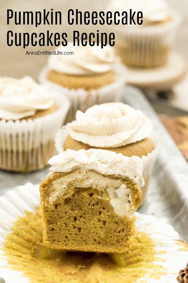 A close-up of a cut open pumpkin cupcake showing the cheesecake filling. There are whole cupcakes surrounding this cupcake.