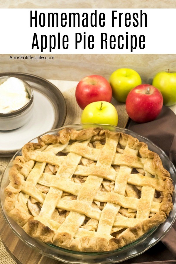 A homemade apple pie with a lattice top sits front and center. There is a scoop of vanilla ice cream in a small bowl in the upper left, 5 apples are in the upper right.