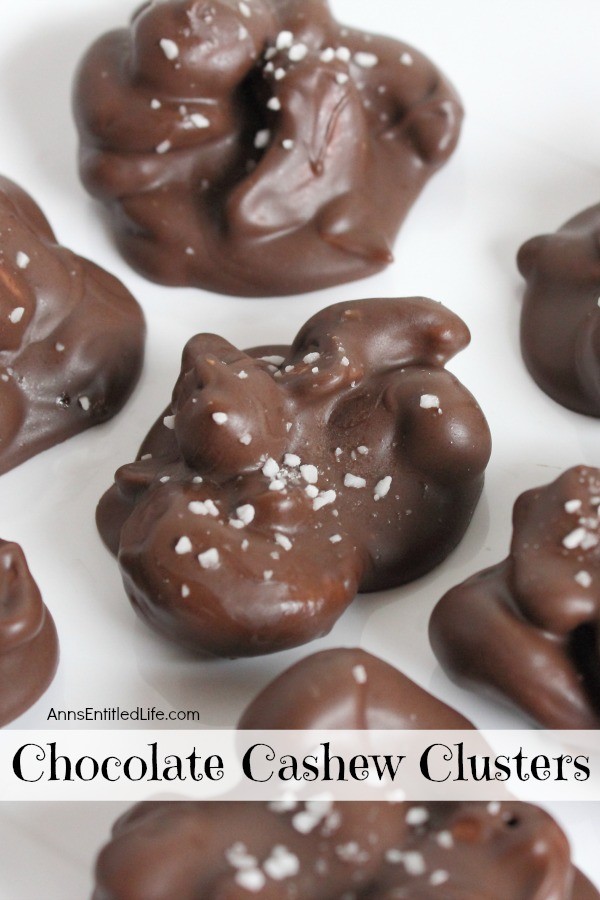 Six homemade chocolate cashew clusters are set on a white paper.