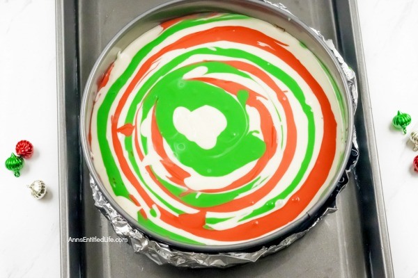 Christmas Cheesecake Recipe. Impress your friends and family with this gorgeous Christmas Cheesecake. You will delight your taste buds when you serve this dressed-up classic sour cream cheesecake recipe for the holidays. The beautiful swirls of color add a dash of magical wonder to match the holiday season and form a perfect holiday dessert.