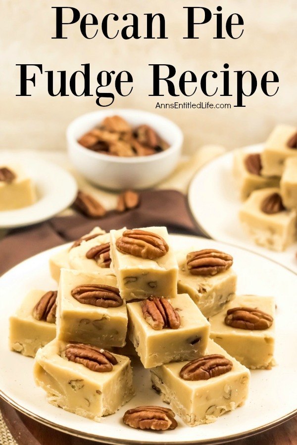 A white plate with gold trim is filled with stacked pieces of pecan pie fudge. In the background is a second plate of fudge in the upper right, a bowl of chopped pecan sits in the center back, and to the back left is a plate with a single piece of pumpkin pie fudge.