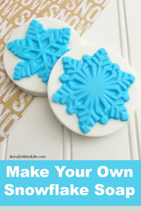 Two round white soap with a blue snowflake in the center (part of the soap) on top of a half whiteboard, half snow sheet.