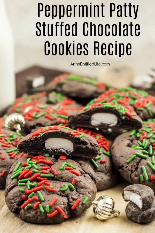 A cutting board filled with chocolate peppermint patty cookies. The top cookie is cut open to show the peppermint patty inside. There are two peppermint patty candies in front, along with a small gold ornament.