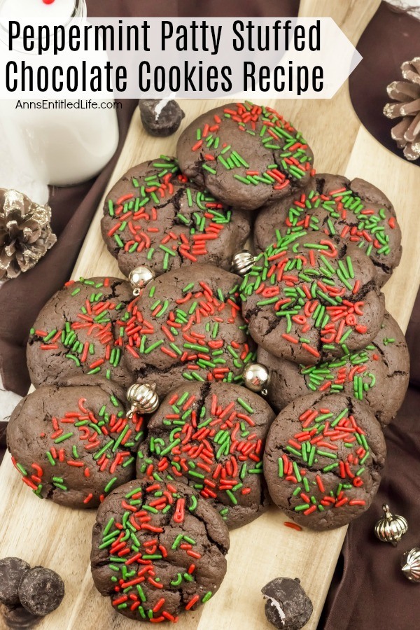 An overhead view of a cutting board filled with peppermint patty chocolate cookies. There are small gold ornaments decorating the pile. There is a glass of milk in the upper left, and peppermint patty cookies decorating the area.