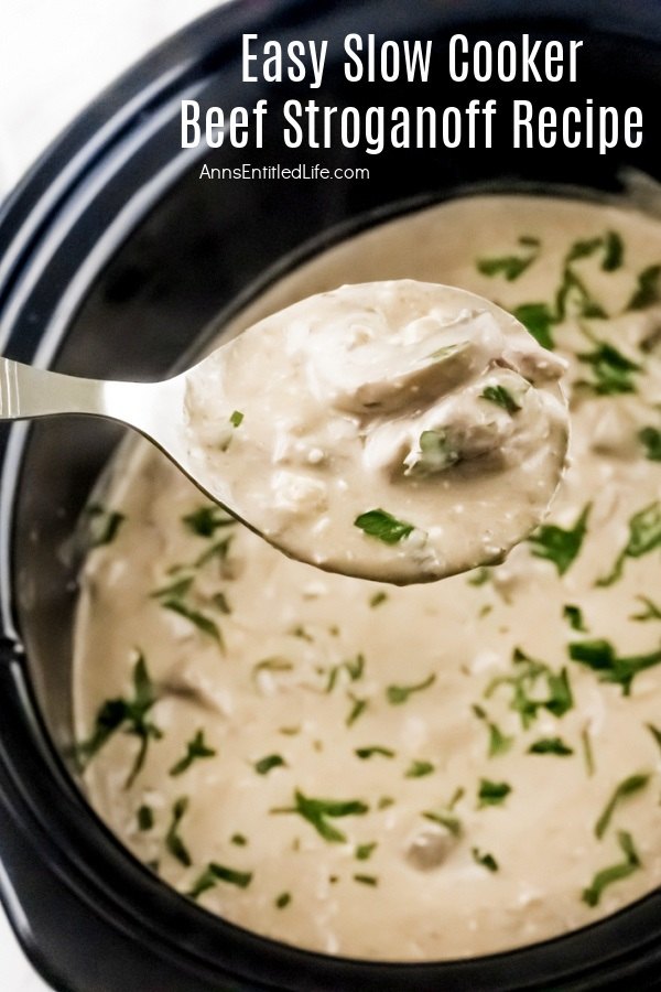 a serving spoon is full of beef stroganoff lifted from the full slow cooker insert below